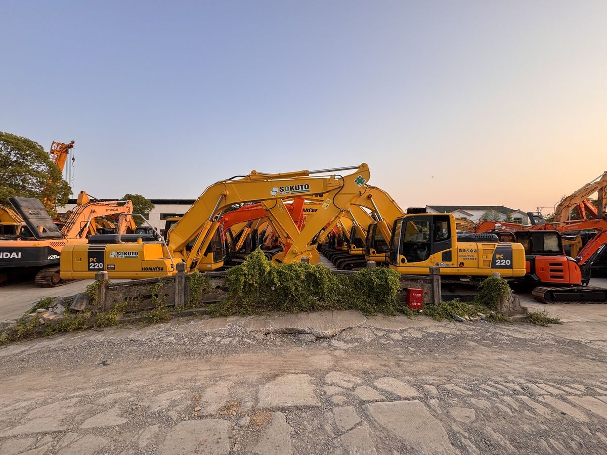Wide view of sourcing facility yard with rows of excavators at dusk