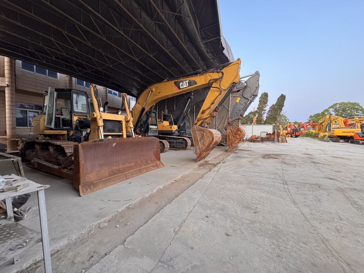 Machines sheltered under canopy — CAT and Volvo excavators