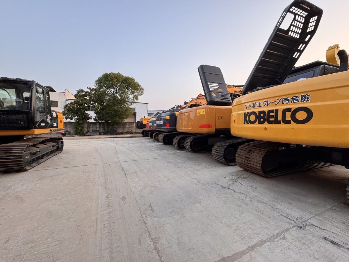 Row of excavators from track level — multiple brands in stock